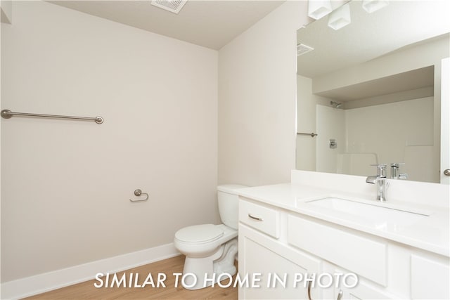 bathroom featuring visible vents, toilet, baseboards, and wood finished floors