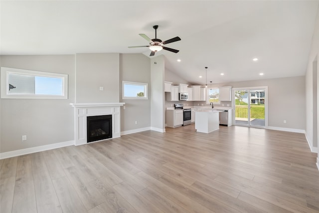 unfurnished living room featuring light hardwood / wood-style flooring, vaulted ceiling, ceiling fan, and sink