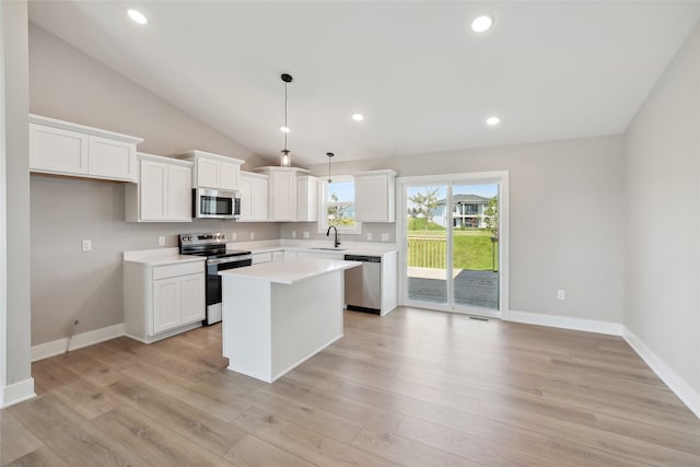 kitchen with appliances with stainless steel finishes, white cabinetry, a kitchen island, light hardwood / wood-style flooring, and sink