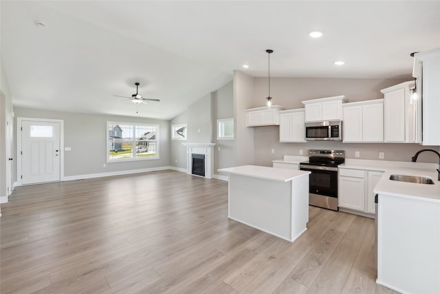 kitchen featuring stainless steel appliances, lofted ceiling, a center island, ceiling fan, and sink