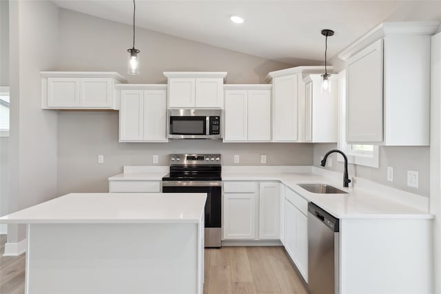 kitchen with white cabinets, appliances with stainless steel finishes, hanging light fixtures, and vaulted ceiling