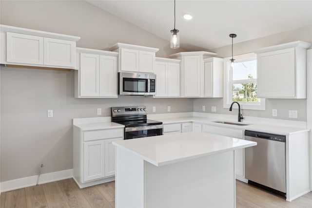 kitchen with pendant lighting, white cabinets, sink, appliances with stainless steel finishes, and vaulted ceiling