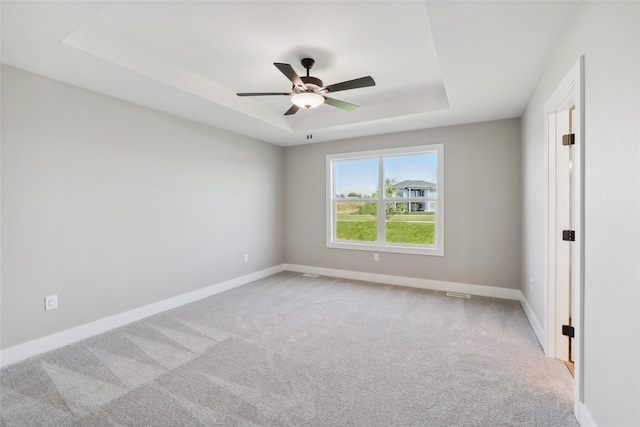 carpeted spare room featuring ceiling fan and a tray ceiling