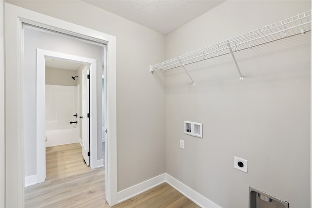 washroom featuring washer hookup, a textured ceiling, light wood-type flooring, and electric dryer hookup