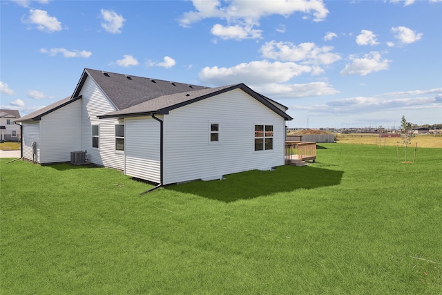 back of property with central air condition unit and a yard