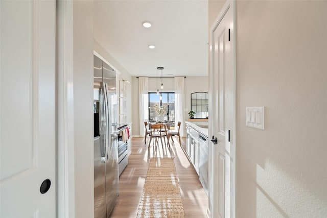 kitchen with hardwood / wood-style flooring, white cabinets, hanging light fixtures, and appliances with stainless steel finishes