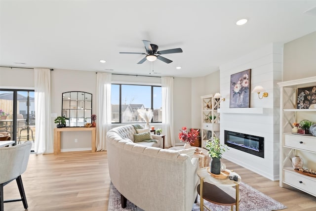 living room with light wood-type flooring, ceiling fan, and plenty of natural light