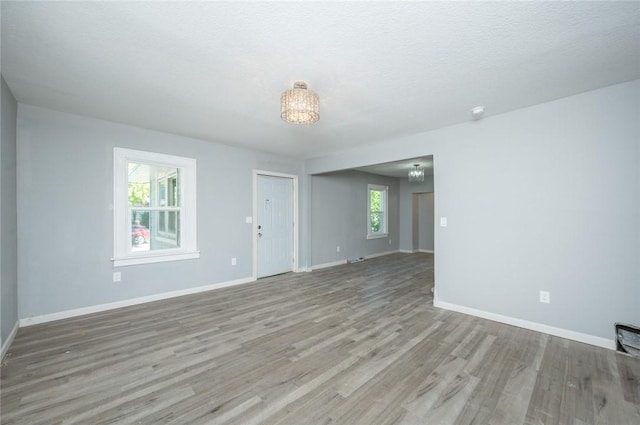 1613 York St, Des Moines, IA 50316 - empty room with wood finished floors, a chandelier, and a textured ceiling