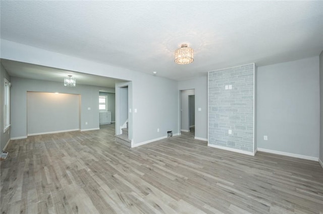 1613 York St, Des Moines, IA 50316 - unfurnished living room featuring a chandelier, stairway, and light wood finished floors