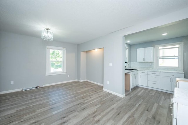 1613 York St, Des Moines, IA 50316 - kitchen featuring light wood-style floors, light countertops, white cabinetry, a chandelier, and open floor plan