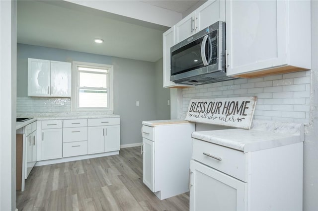 1613 York St, Des Moines, IA 50316 - kitchen with stainless steel microwave, decorative backsplash, light wood-style floors, white cabinetry, and light countertops