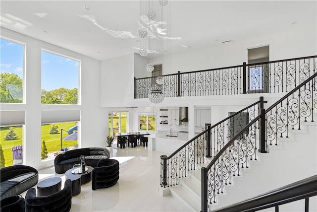 stairway featuring sink, tile flooring, a high ceiling, and a chandelier