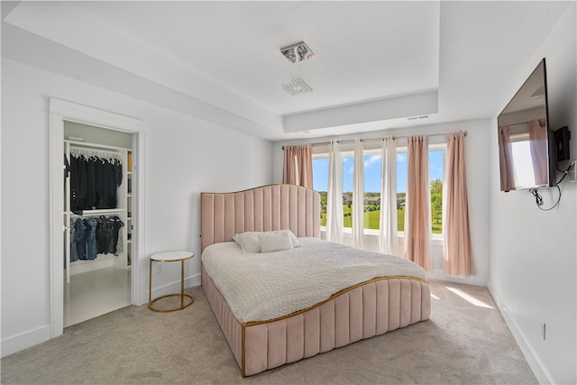 bedroom with a tray ceiling, a closet, and light colored carpet