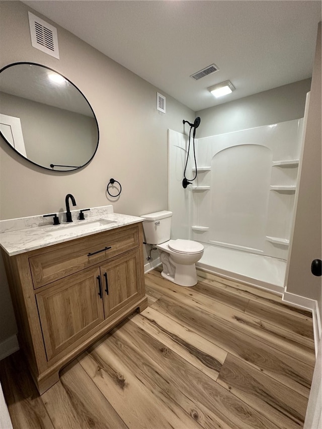 bathroom featuring hardwood / wood-style floors, toilet, a shower, and vanity