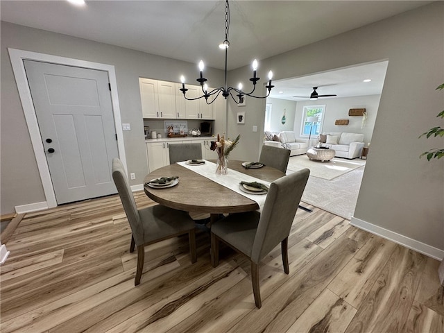 dining room featuring light hardwood / wood-style floors and ceiling fan with notable chandelier