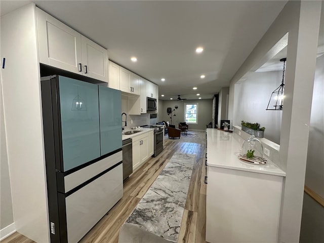 kitchen with appliances with stainless steel finishes, light hardwood / wood-style flooring, white cabinetry, and sink