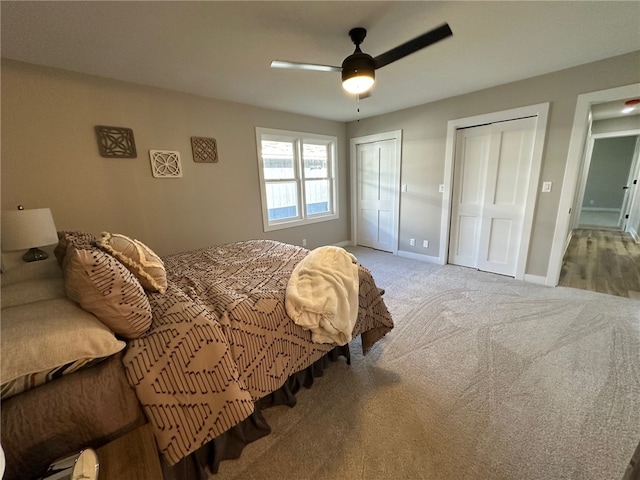 bedroom featuring two closets, light colored carpet, and ceiling fan