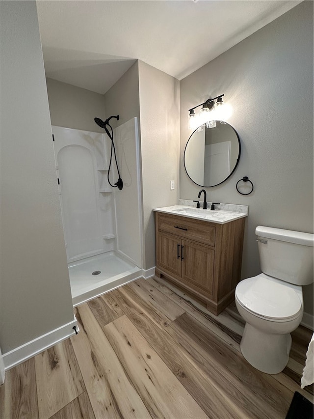 bathroom featuring toilet, vanity, wood-type flooring, and walk in shower