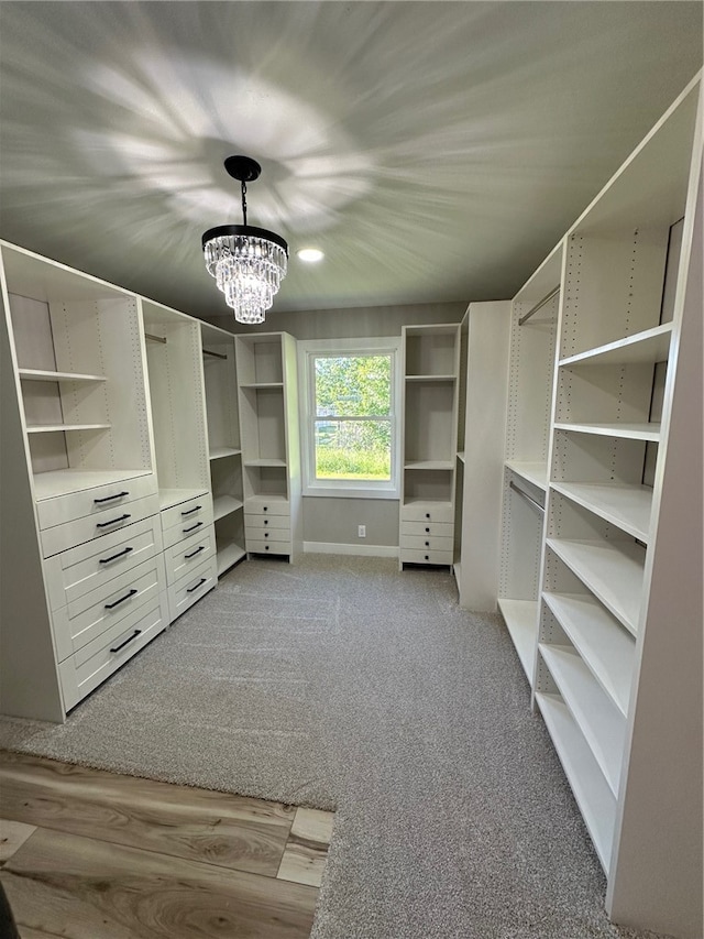 walk in closet featuring light carpet and a notable chandelier