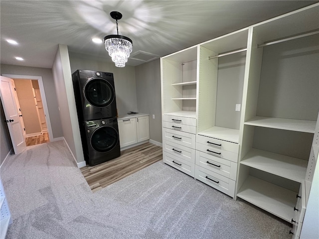 walk in closet with stacked washer / dryer, a chandelier, and light hardwood / wood-style floors