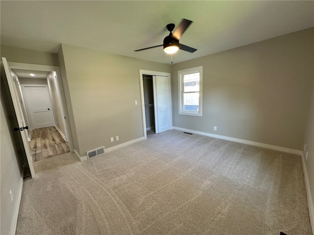 unfurnished bedroom with a closet, ceiling fan, and light colored carpet