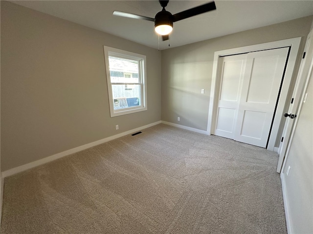 unfurnished bedroom featuring ceiling fan, light carpet, and a closet