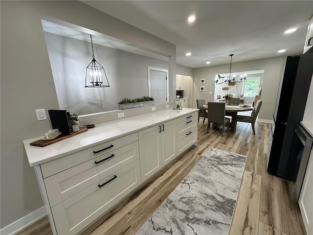 kitchen featuring white cabinetry, pendant lighting, a notable chandelier, and light wood-type flooring