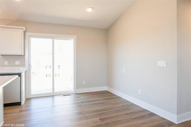 unfurnished dining area with visible vents, baseboards, and wood finished floors