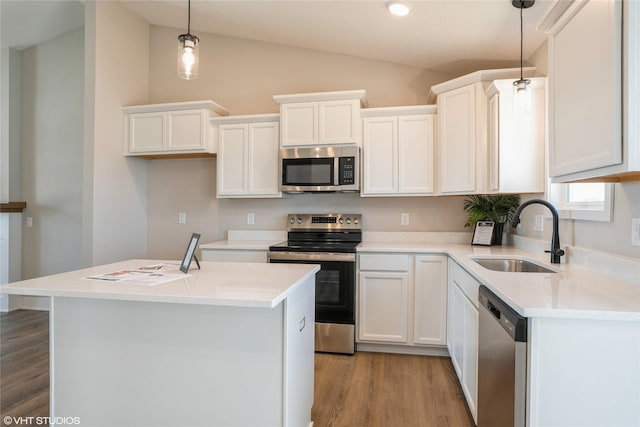 kitchen with vaulted ceiling, stainless steel appliances, a sink, and white cabinetry