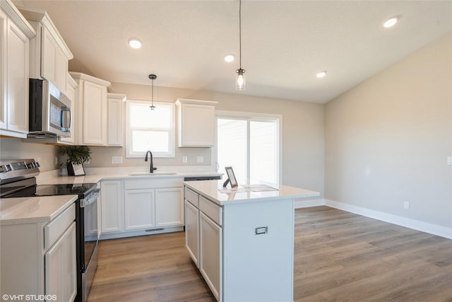 kitchen featuring appliances with stainless steel finishes, a kitchen island, a sink, and light wood-style flooring