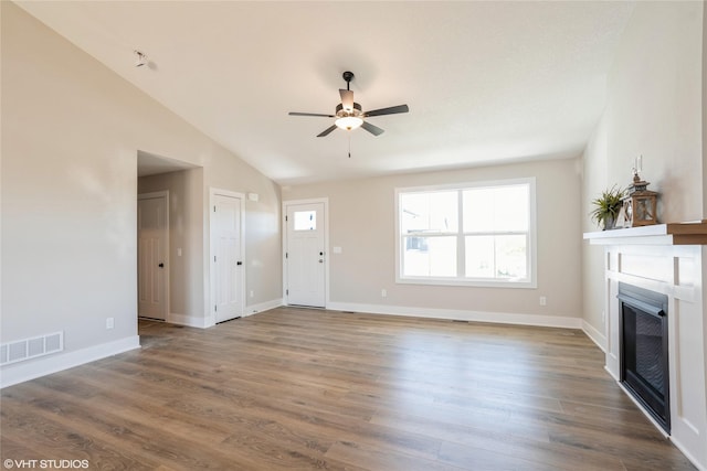 unfurnished living room with a fireplace, lofted ceiling, visible vents, ceiling fan, and wood finished floors