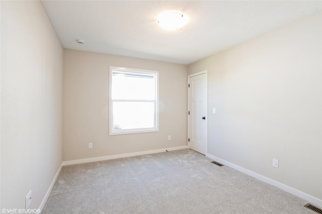 empty room with baseboards, visible vents, and light colored carpet