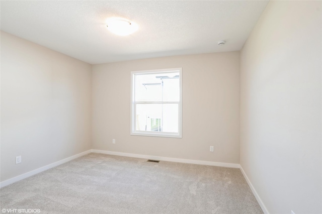 unfurnished room with baseboards, a textured ceiling, visible vents, and light colored carpet