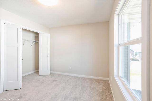 unfurnished bedroom with baseboards, a closet, and light colored carpet