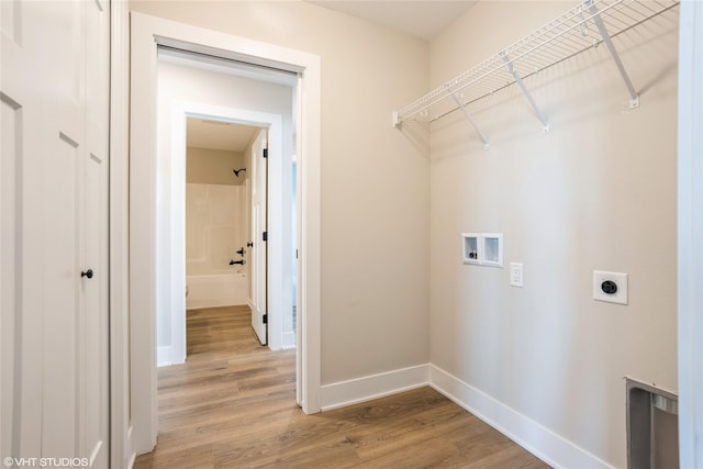 clothes washing area featuring light wood-style flooring, hookup for an electric dryer, laundry area, washer hookup, and baseboards