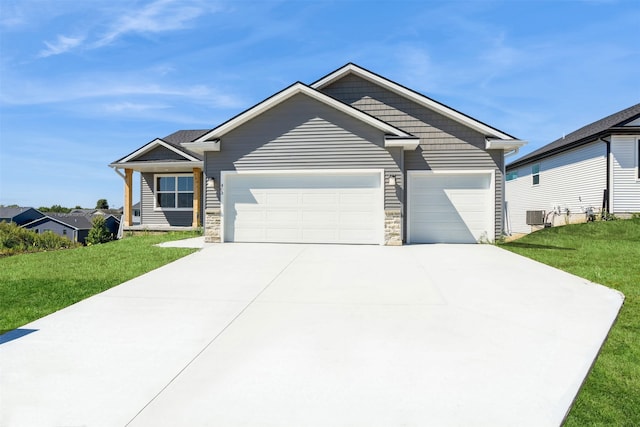 view of front facade featuring a garage, stone siding, driveway, and a front yard