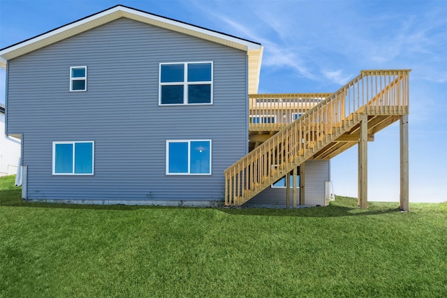 rear view of property with stairway, a wooden deck, and a lawn