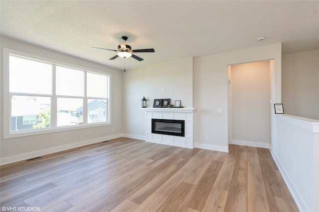 unfurnished living room featuring light hardwood / wood-style flooring, ceiling fan, and a textured ceiling