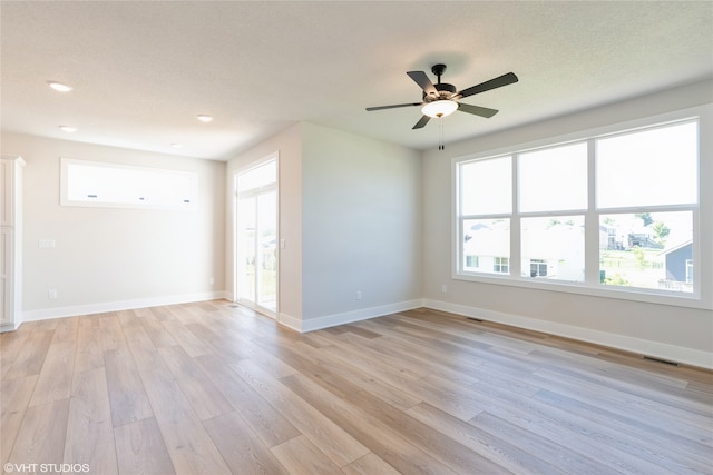 spare room featuring light hardwood / wood-style flooring, a wealth of natural light, and ceiling fan