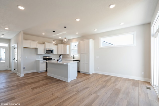 kitchen with stainless steel appliances, hanging light fixtures, plenty of natural light, and a kitchen island