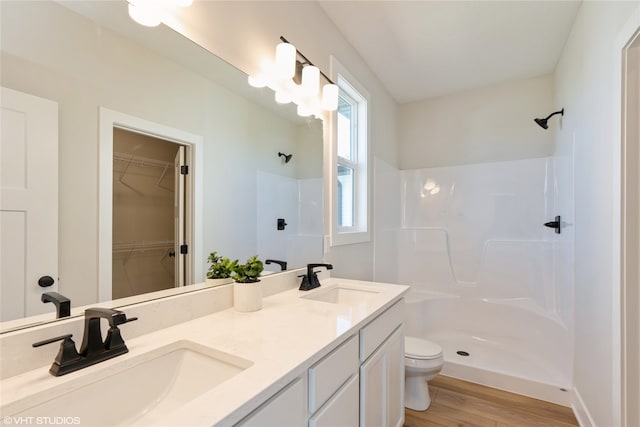 bathroom with hardwood / wood-style floors, a shower, vanity, and toilet