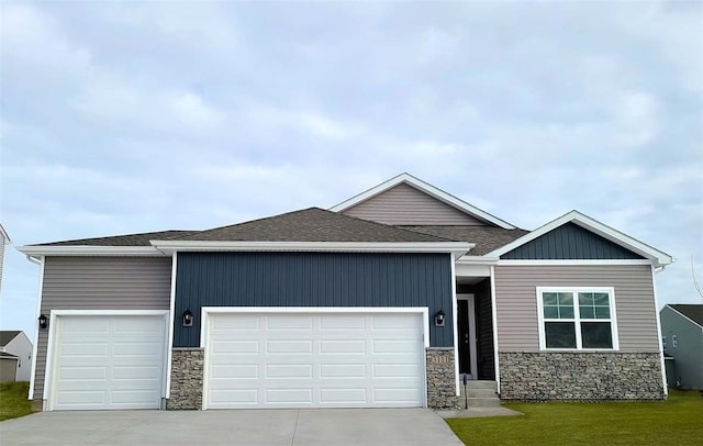 view of front of property featuring an attached garage, stone siding, driveway, and roof with shingles