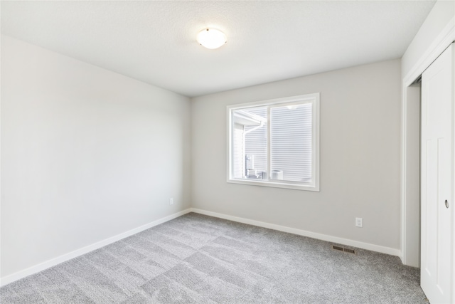 unfurnished bedroom featuring light carpet and a closet