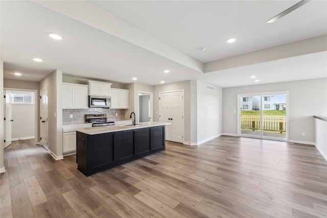 kitchen with a kitchen island with sink, white cabinets, stainless steel appliances, and hardwood / wood-style flooring