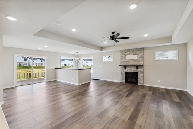 unfurnished living room featuring dark hardwood / wood-style floors, a fireplace, and ceiling fan with notable chandelier