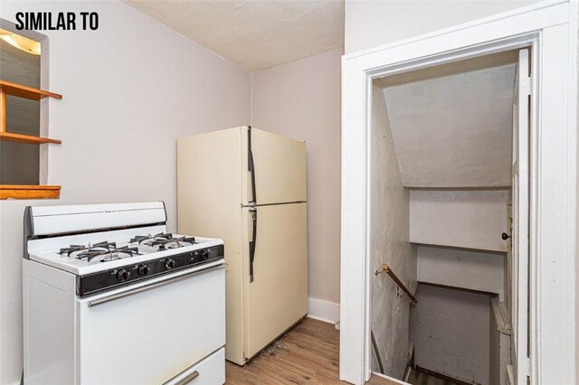 kitchen featuring white appliances, lofted ceiling, white cabinetry, and light hardwood / wood-style flooring