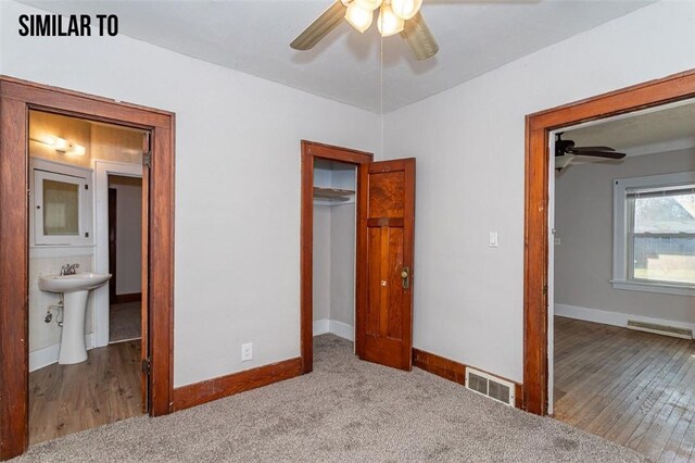 unfurnished bedroom featuring hardwood / wood-style floors, ensuite bath, and ceiling fan