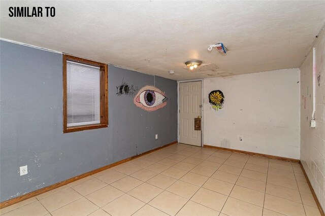 unfurnished room featuring a textured ceiling and light tile flooring