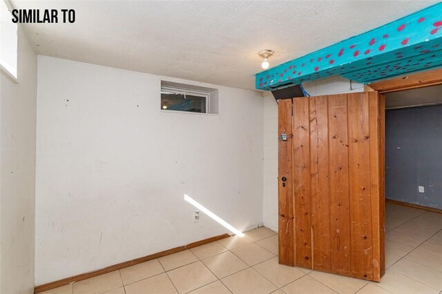 spare room featuring a textured ceiling and light tile floors