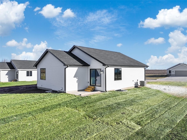 rear view of house with cooling unit and a lawn